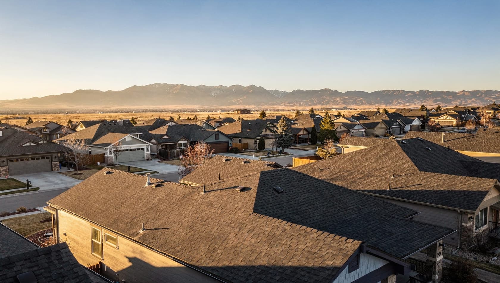 Highlands Ranch rooftops receding toward the Colorado Front Range foothills at golden hour